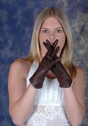 Blonde female pulls on brown leather gloves while wearing a white dress on tubephoto.pics