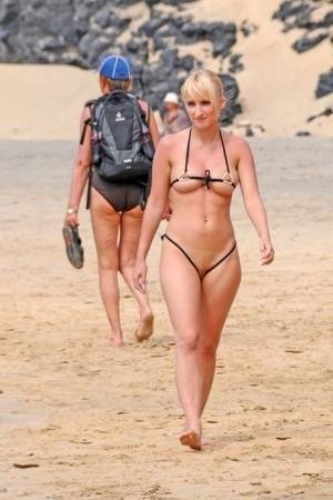 Hot blonde removes a skimpy bikini during a visit to a public beach on tubephoto.pics